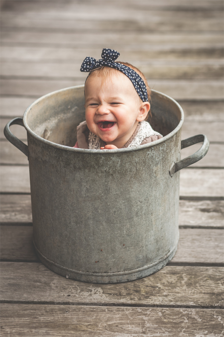 Ein Kind sitzt vergnügt in einem Eimer und lacht